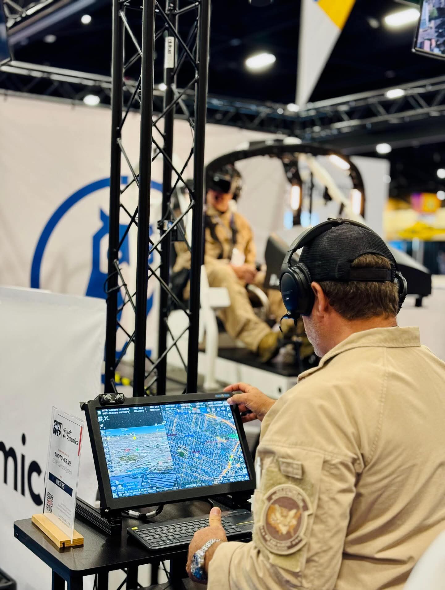 Operator using the SHOTOVER M2 simulator touchscreen beside a Loft Dynamics helicopter simulator